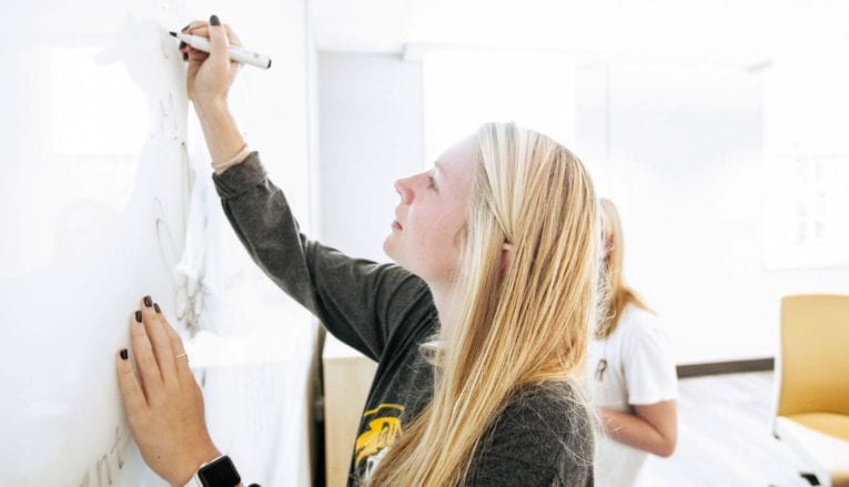 woman student writing on whiteboard