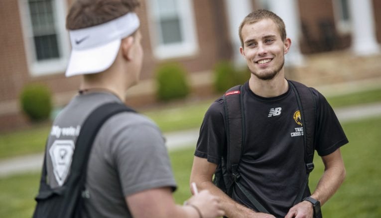 two male students talking outside and smiling