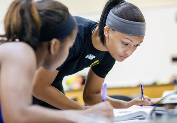 two female students leaning over and writing