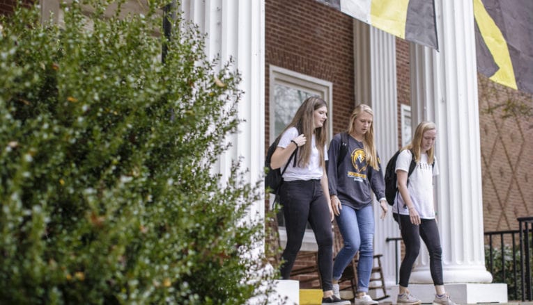 three female students walking out of campus building