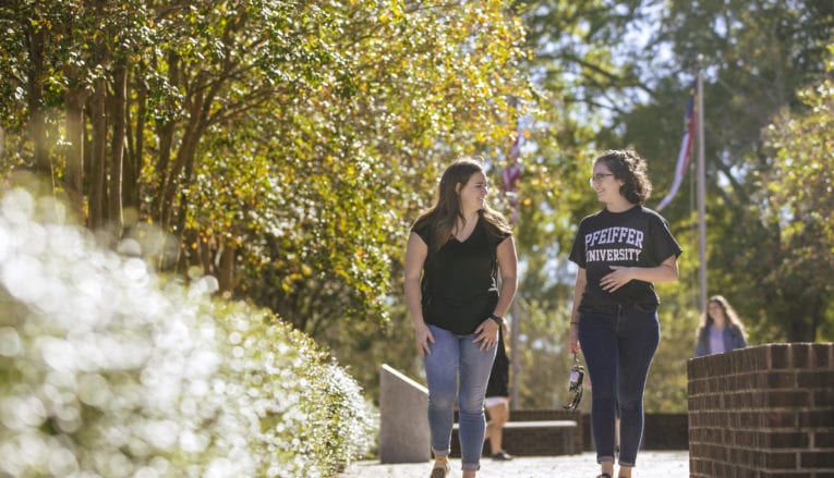 two women walking and talking on sidewalk