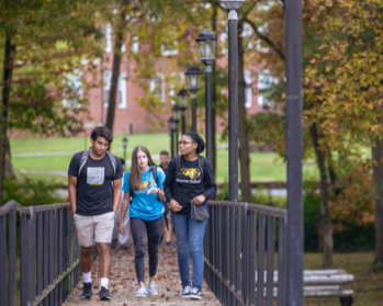 3 students walking on bridge outside