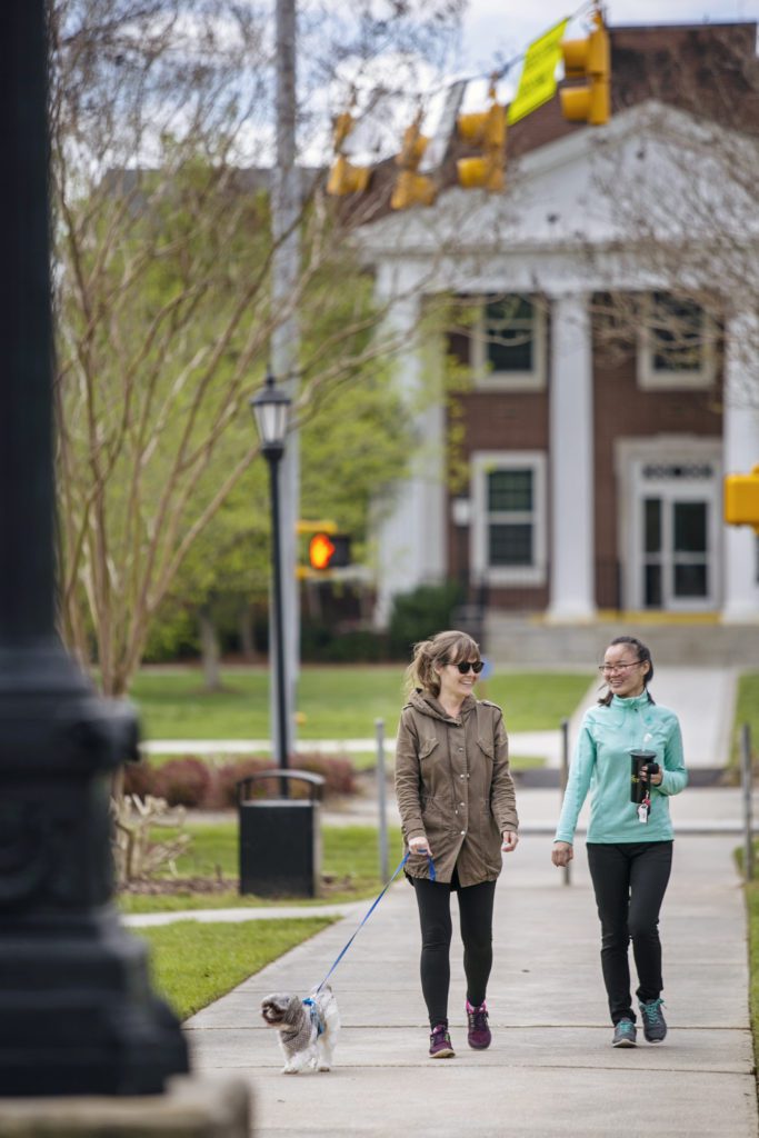 Two students outside walking dog