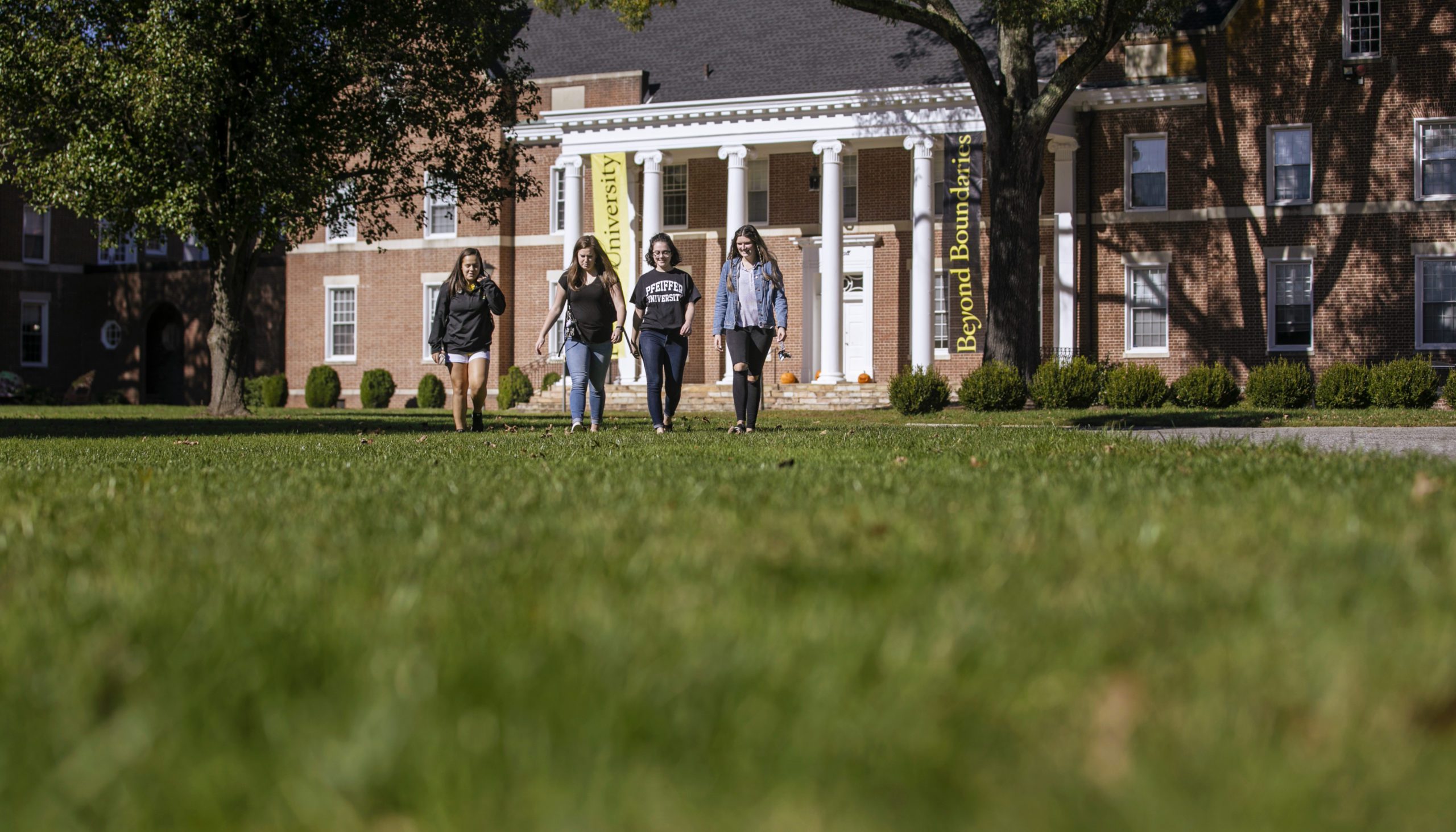 Group of students walking across campus lawn